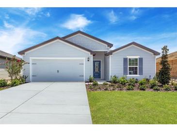 Two-car garage and front entrance of a charming light gray house with landscaping at 4270 Sw 143Rd Lane Rd, Ocala, FL 34473