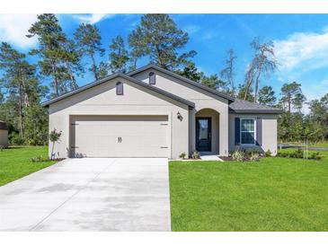 House exterior with a two-car garage and landscaped yard at 16448 Sw 17Th Terrace Rd, Ocala, FL 34473