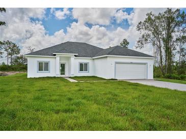 Single story home with a two-car garage and grassy yard at 7811 Red Grange Blvd, Indian Lake Estates, FL 33855