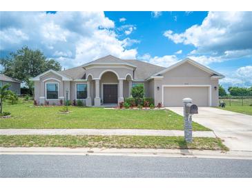 Single-story home with tan exterior, arched entryway, and two-car garage at 4046 Dinner Lake Way, Lake Wales, FL 33859