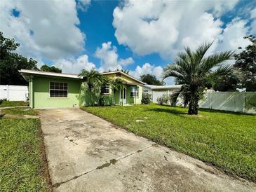 Ranch-style home with a green exterior, driveway, and palm tree at 6004 Hilltop E Ln, Lakeland, FL 33809