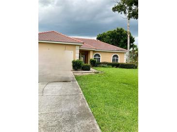 Single-story home with a red tile roof and a large grassy yard at 417 Bay Leaf Dr, Kissimmee, FL 34759