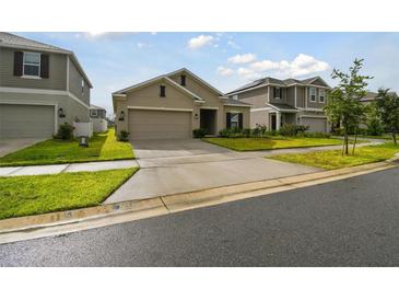 Tan two-car garage house with landscaping and driveway at 1122 James Paul Rd, Davenport, FL 33837