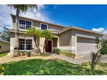 Two-story house with a beige exterior, landscaped yard, and a two-car garage at 4615 Cumbrian Lakes Dr, Kissimmee, FL 34746