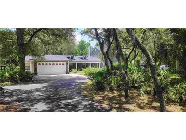 Two-story home with a large driveway and mature landscaping at 14815 Lake Pickett Rd, Orlando, FL 32820