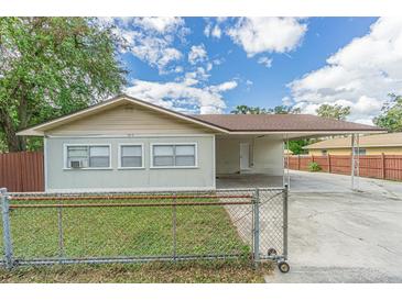 Tan house with carport, fenced yard, and mature trees at 910 N Lincoln Ave, Lakeland, FL 33815