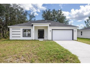 Newly constructed home with a white exterior, gray roof, and a two-car garage at 1312 Congo Dr, Kissimmee, FL 34759