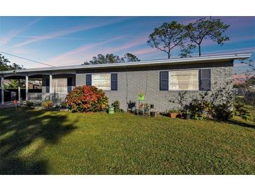 Gray brick ranch home with a covered porch, well-manicured lawn, and mature landscaping at 1019 Milner E Dr, Lakeland, FL 33810