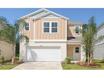 Two-story house with a beige exterior, white garage door, and landscaping at 1418 Derry Ave, Haines City, FL 33844