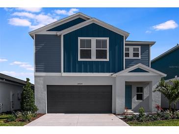 Two-story house with gray and blue siding, two-car garage, and landscaping at 1422 Derry Ave, Haines City, FL 33844