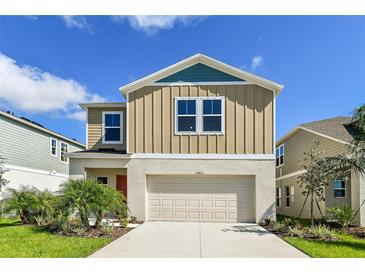 Two-story house with beige and teal siding, two-car garage, and landscaping at 4002 Gardenia Ave, Lake Hamilton, FL 33851