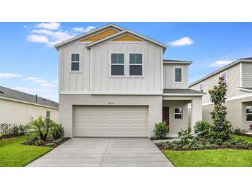 Two-story house with a beige exterior, two-car garage, and landscaping at 4014 Gardenia Ave, Lake Hamilton, FL 33851