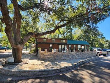 Log cabin home with green metal roof, stone wall, and spacious patio at 25232 Ne 142Nd St, Fort Mc Coy, FL 32134