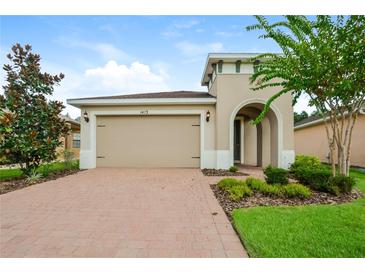Beige one-story home with arched entryway and attached two-car garage at 1423 Harbor Ridge Dr, Poinciana, FL 34759