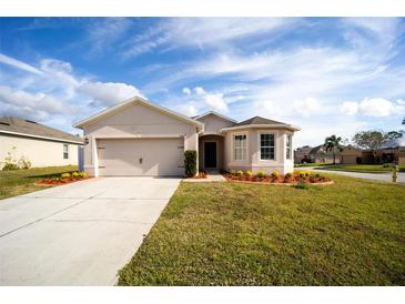 Tan house with a two-car garage, landscaping, and a paved driveway at 1046 Roberta Rd, Lake Wales, FL 33853