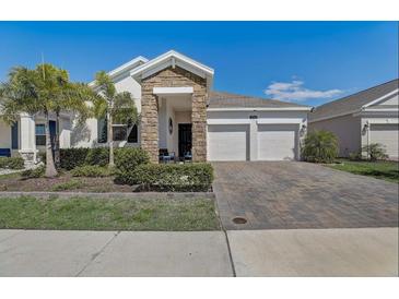 Attractive single-story home with a stone and stucco facade, paver driveway, and lush landscaping at 1767 Bee Nice Dr, Kissimmee, FL 34744