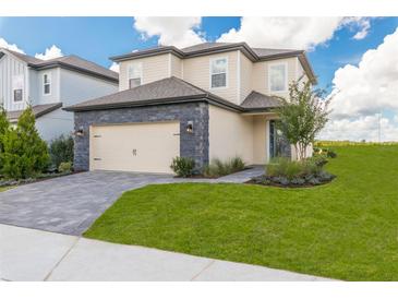 Two-story home with a paved driveway, landscaped yard, and attached garage at 7861 Somersworth Dr, Kissimmee, FL 34747