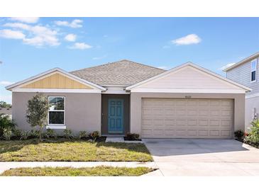 One-story house with gray siding, beige garage door, and teal front door at 1106 Foreshore Ln, Haines City, FL 33844