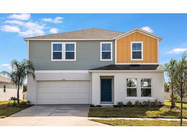 Two-story house with gray and orange siding, white garage door, and teal front door at 725 Ambleside Dr, Haines City, FL 33844