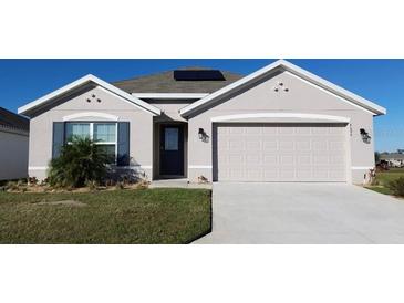 One-story home with attached garage, solar panels, and landscaped lawn at 4694 Sigcom Pl, Wildwood, FL 34785