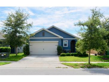 Blue house with a beige garage door and landscaping at 226 Meghan Cir, Deland, FL 32724