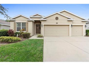 Tan house with two-car garage and manicured lawn at 509 W Victoria Trails Blvd, Deland, FL 32724