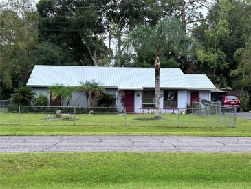 Single story home with metal roof and fenced yard at 24008 Ermine Rd, Astor, FL 32102