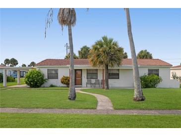 Charming single story home with red tile roof, lush lawn, and palm trees at 133 Cardinal Dr, Ormond Beach, FL 32176