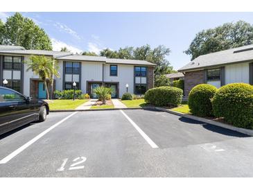 Two-story townhome with light gray siding, teal doors, and manicured landscaping at 12 Arbor Lake Park, Ormond Beach, FL 32174