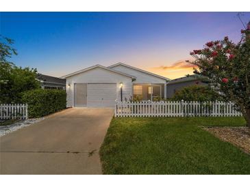 White single story home with attached garage, and white picket fence at 1106 Carvello Dr, The Villages, FL 32162