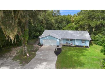 Cute blue house with a metal roof, two car garage, and large yard at 288 Silverstone Dr, Orange City, FL 32763