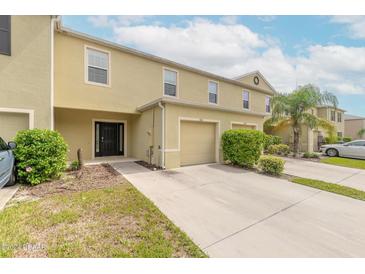 Front view of a two-story townhome with a two-car garage and landscaping at 1631 Primo Ct, Holly Hill, FL 32117