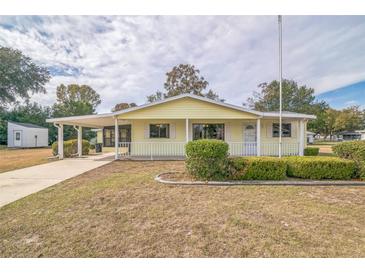 Cute yellow house with carport and well-manicured landscaping at 10170 Sw 96Th Ct, Ocala, FL 34481