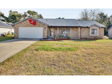 Brick house with gray metal roof, attached garage, and well-maintained lawn at 2585 Delbarton Ave, Deltona, FL 32725