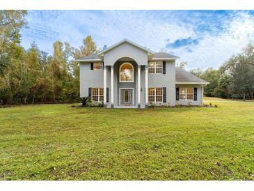 Two-story house with gray siding, large windows, and a spacious lawn at 1907 Enterprise Osteen Rd, Deltona, FL 32738