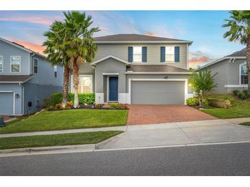 Two-story house with gray siding, brick driveway, and palm trees at 3404 Grassy Lake View Ave, Minneola, FL 34715