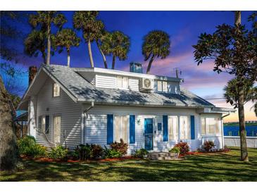 Charming white house with blue shutters, landscaped yard, and waterfront view at 101 Fleming Ave, Port Orange, FL 32127