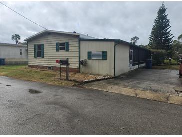 Single-wide mobile home with green trim and a screened porch at 1632 Bream Dr, Seville, FL 32190