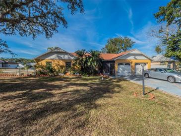 Single-story home with a two-car garage and spacious lawn at 902 Millenbeck Ave, Deltona, FL 32725