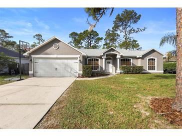 Gray house with two-car garage, nicely landscaped lawn and basketball hoop at 3398 Somerset Ave, Deltona, FL 32738