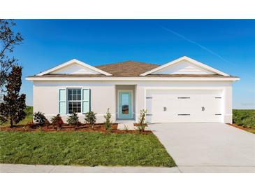 Single-story home with white exterior, teal door, and two-car garage at 1235 Tank Trl, Haines City, FL 33844