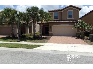 Two-story home with a paved driveway, attached garage, and landscaped front yard at 5537 Misty Oak Cir, Davenport, FL 33837
