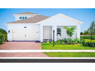 Two-story house with white siding, brick driveway, and landscaping at 10865 Sw 73Rd Ct, Ocala, FL 34476