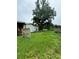 Backyard with overgrown grass, a partially constructed home, and a large tree at 1134 N Davis Ave, Lakeland, FL 33805
