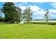 Peaceful lakefront view with lush green grass and mature trees at 1502 Ne Buckeye Ne Rd # 2, Winter Haven, FL 33881