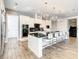 White kitchen features a large island with seating, stainless steel appliances, and hardwood floors at 550 Muirfield Loop, Reunion, FL 34747