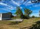 Side view of a single-story house with gravel driveway and trees at 129 Constitution Ln, Frostproof, FL 33843