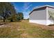 Side view of a gray single-story home with white skirting, situated on a grassy lot with trees at 129 Constitution Ln, Frostproof, FL 33843