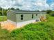 Green mobile home with wooden deck and steps, situated on a large lot at 10109 Old Spanish Trl, Polk City, FL 33868