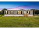 Single-wide manufactured home with gray siding, wooden steps, and a grassy yard at 10109 Old Spanish Trl, Polk City, FL 33868